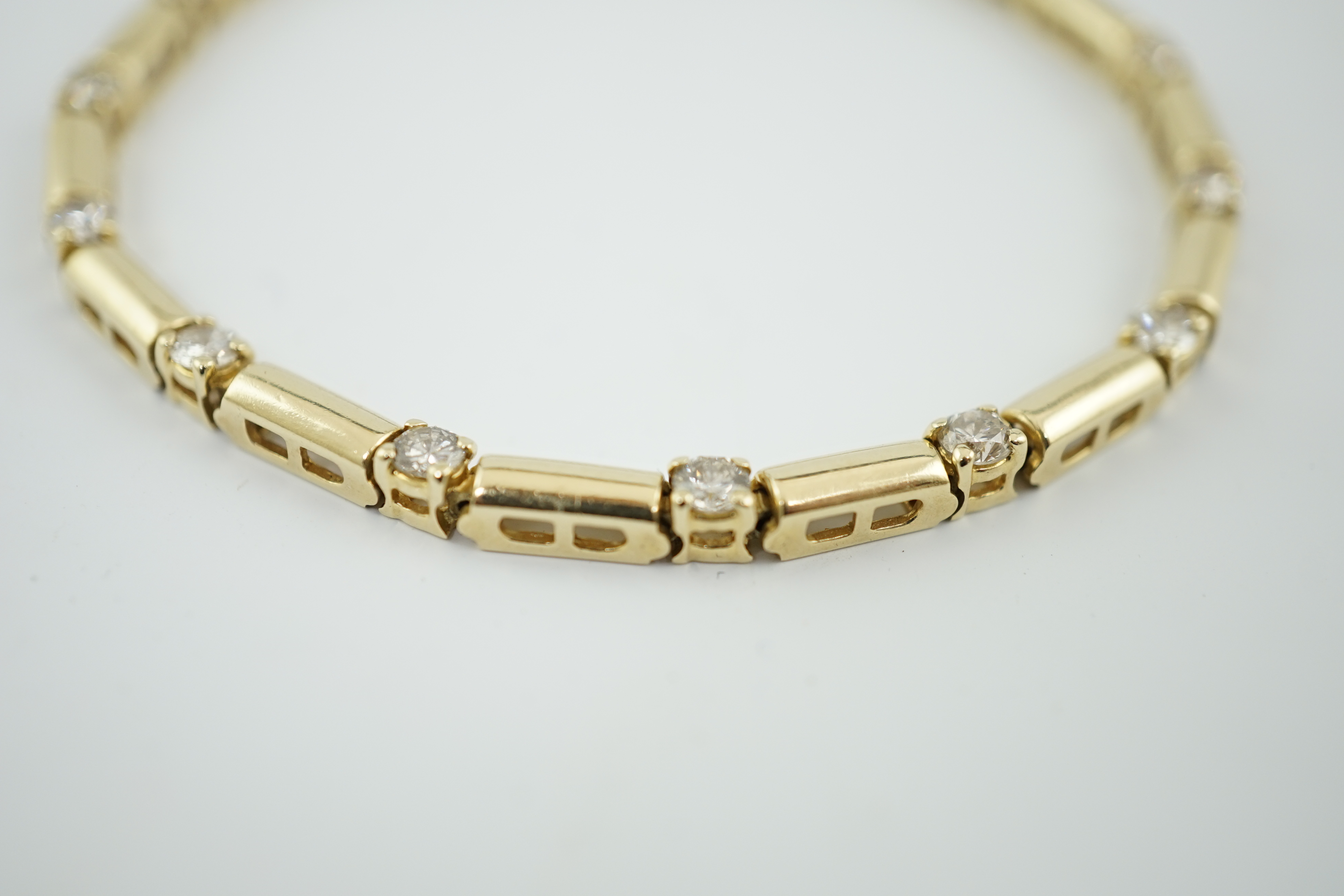 A modern 14k gold and fifteen stone diamond set line bracelet